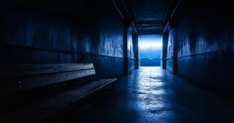 Dim tunnel with a bench leading to a brightly lit arena entrance